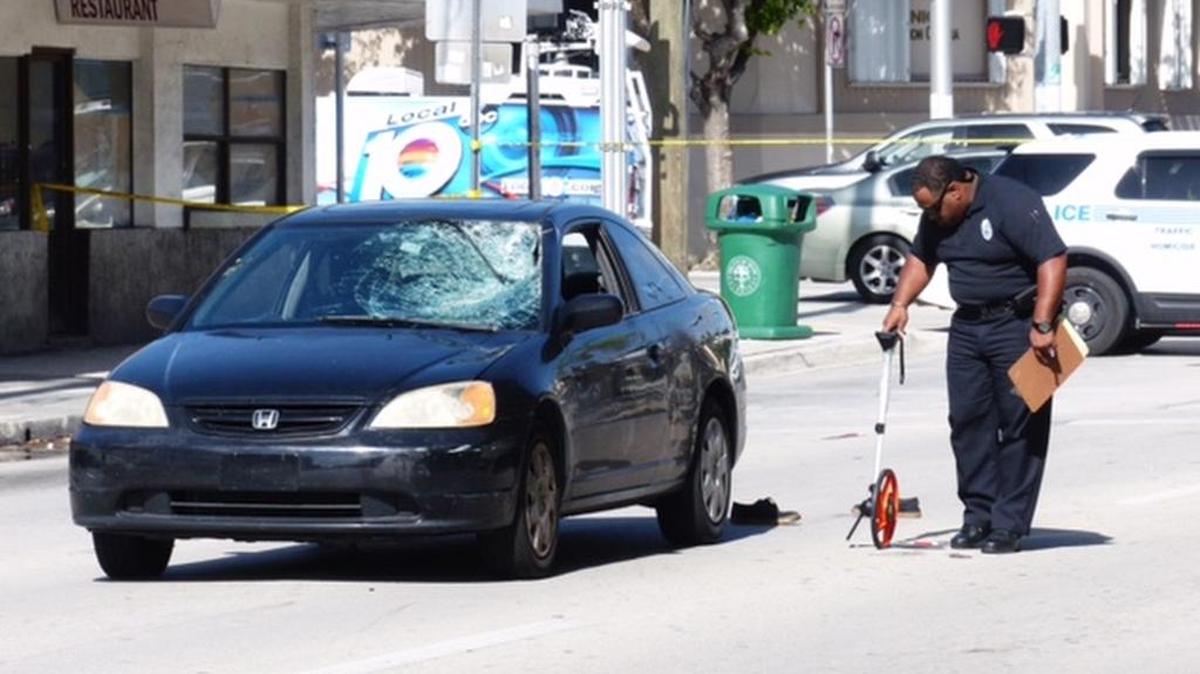 A Miami police official invesigates the scene Monday at Southwest First Street between 11th Avenue and 10th Avenue.