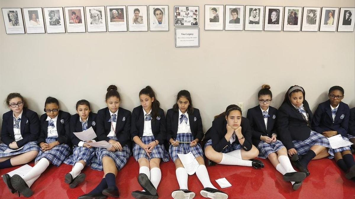 Sixth-graders sit under portrait of global successful women as they listen to banker Sandy Londono from Sabadell Bank during her visit.