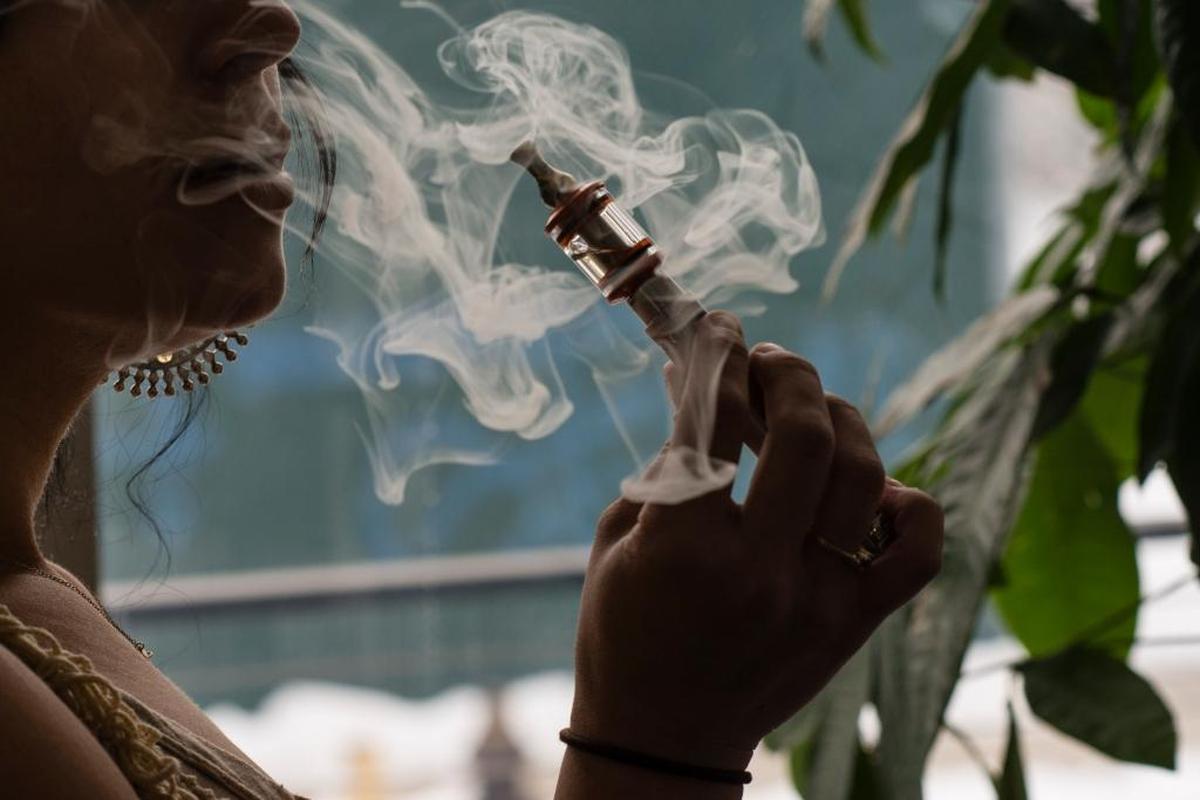 A woman smokes from a vaping device.