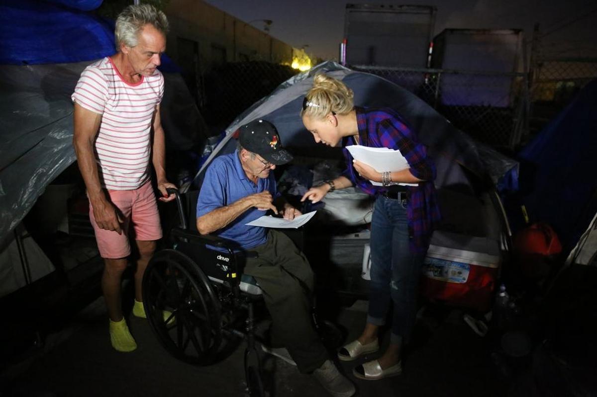 Lauren Book, a Democratic senator from Broward and a survivor of child sexual abuse, gives paperwork to homeless sexual offenders, Claudia Marie Baker (L) and Luis Concepcion at a homeless camp for sexual offenders near Hialeah, Monday night, August 21, 2017. Miami-Dade is taking action against the homeless encampment of sexual offenders. Homeless Trust workers alongside city employees and police officers, canvased the tents to talk to their occupants about finding them places to live that don’t conflict with county rules on how close offenders can be to schools and parks.