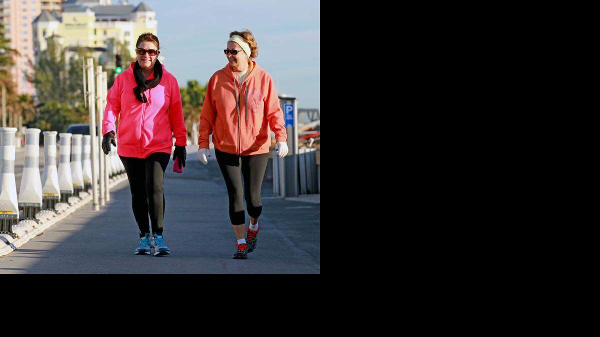 
Jennie DiRosa and Jenny Boese take their daily walk along Fort Lauderdale Beach dressed for the dip in temperatures as a cold front moved through South Florida, Jan. 17, 2014.
