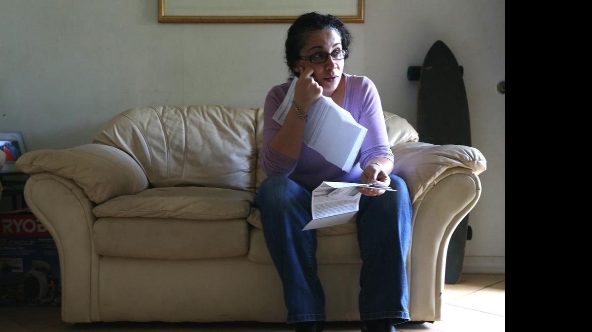 Angela Denig, who has chosen to live without health insurance and pay the Affordable Care Act penalty for being uninsured, holds her medical bills in her Margate home. Months after Denig, 41, chose to pay the penalty, she was diagnosed with a benign tumor in her breast and the cost of surgeries soaked up her savings.