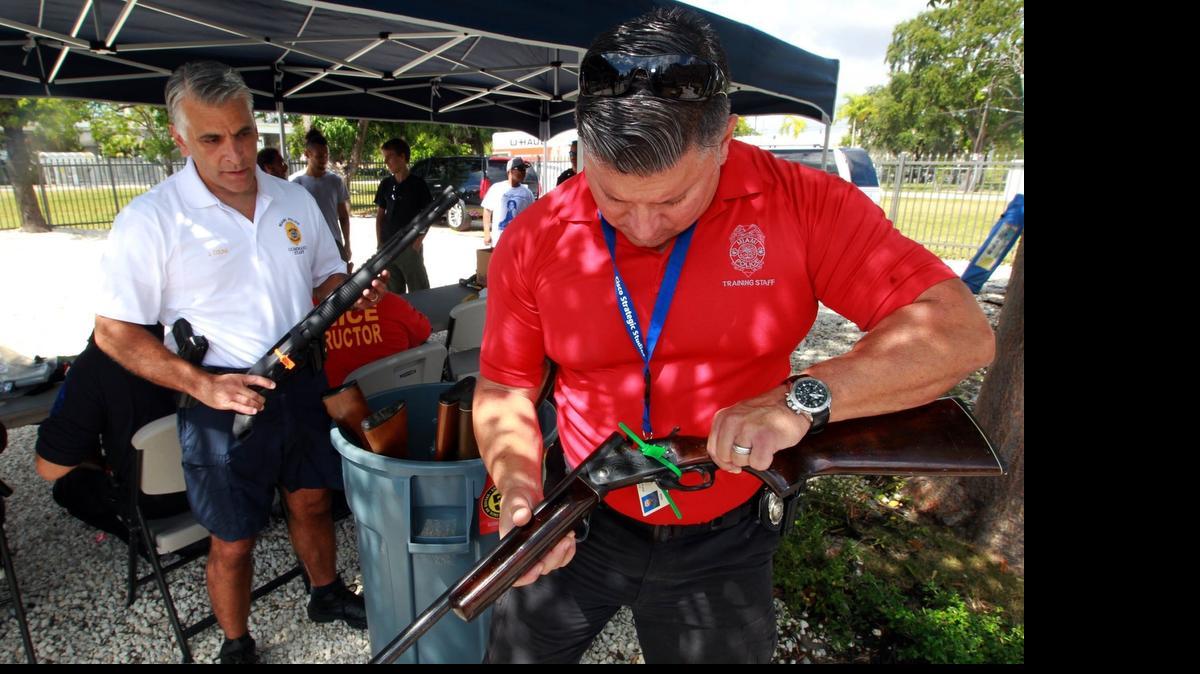 
Officers Luis Gonzalez (right) and Jorge Colina of the Miami Police Department check out a shotgun during a gun buyback program on Saturday, May 30, 2015. Anyone turning in a gun would receive a bicycle, no questions asked; gift cards were also available.
