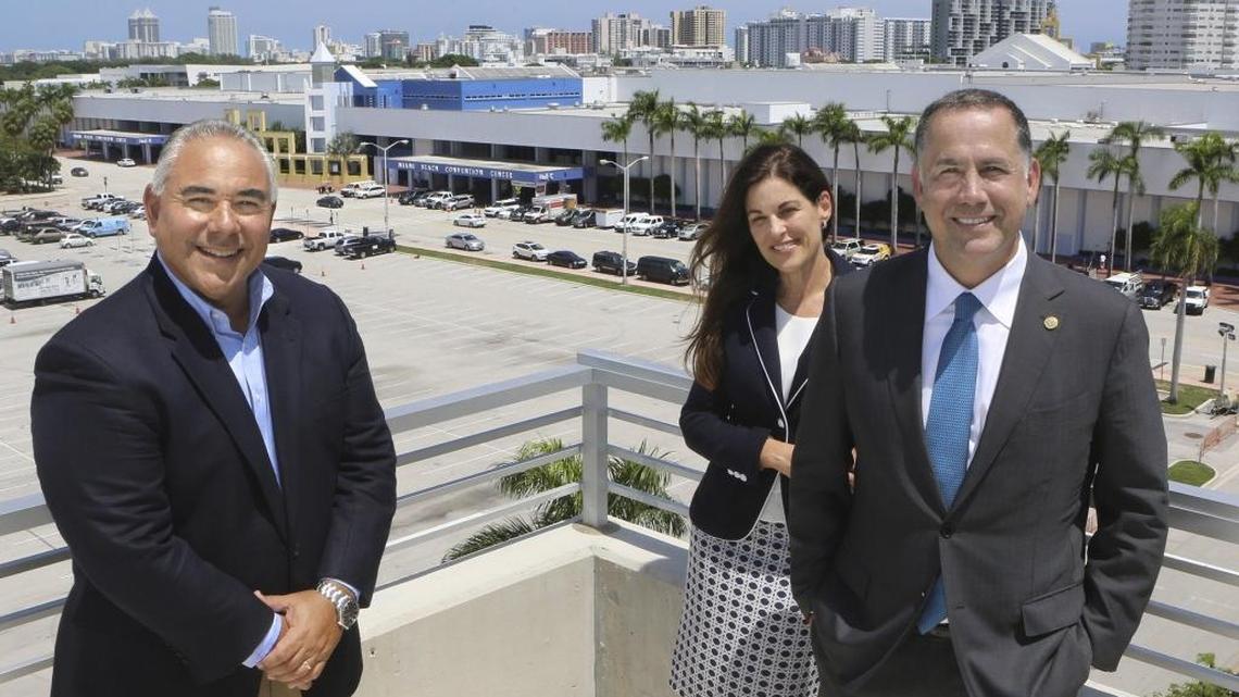 In September: Miami Beach City Manager Jimmy Morales, left, Convention Center District Project Director Maria Hernandez, and Miami Beach Mayor Philip Levine stand on the City Hall parking garage rooftop with the vast backdrop of the Miami Beach Convention Center.