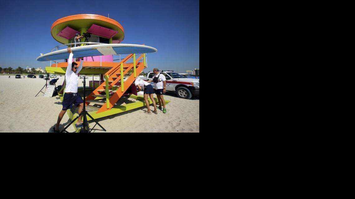 
Miami Beach Lifeguard/EMT Jason Casanova carries a rescue paddle board past his new work station on Friday, March 20, 2015, after a ribbon-cutting ceremony at which Miami Beach officials unveiled one of the city's two new lifeguard towers. This brightly-colored structure is on the beach at 10th Street, behind Ocean Rescue headquarters. Casanova and fellow lifeguard/EMT Cayetano Garcia will team up at this post to keep beachgoers safe. The new towers are added to the already-iconic 29-piece collection between South Pointe and 87th Street. The new round tower's color scheme is ice plant green, fusion pink and knockout orange.

