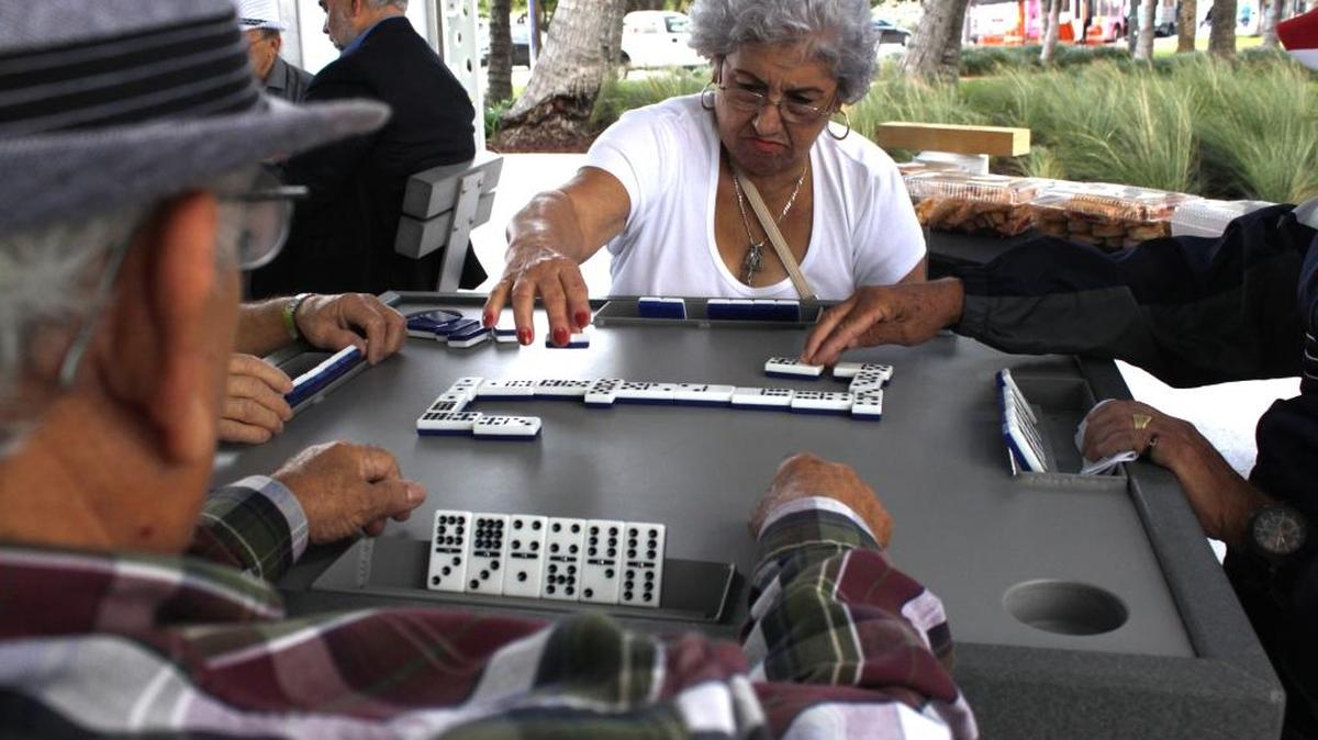 Mercedes Castro, 62, puts a tile down at the new domino pavilion in North Beach Bandshell Park.