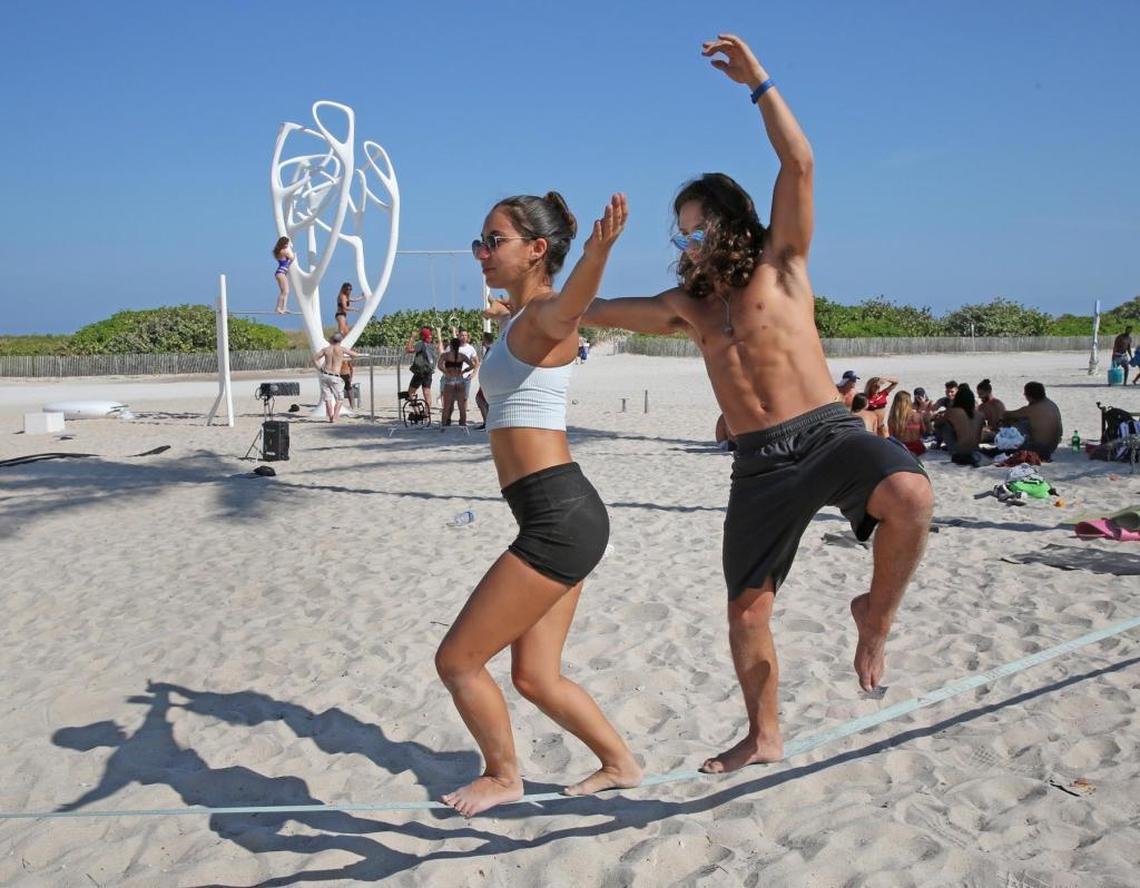 Ishani Falconi and Rodolfo Rojas keep their balance on a tandem slack line on Ocean Drive and Eighth Street Tuesday after the weekend’s spring break crowds fade.