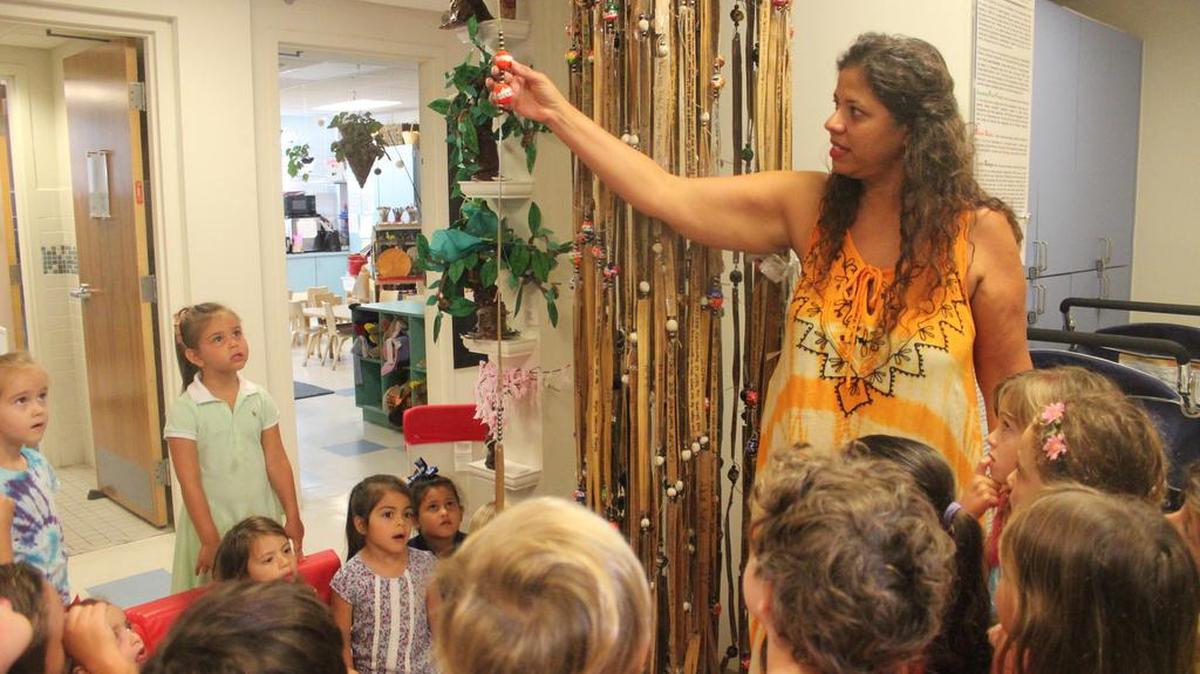 Liset Leyva Santalo, a lead teacher at The Foundation School at Temple Beth Sholom, shows pre-kindergartners the Calder bead on the Shema Listening Tree. The bead honors Calder Sloan, a former student, who was electrocuted while swimming in his pool two years ago.