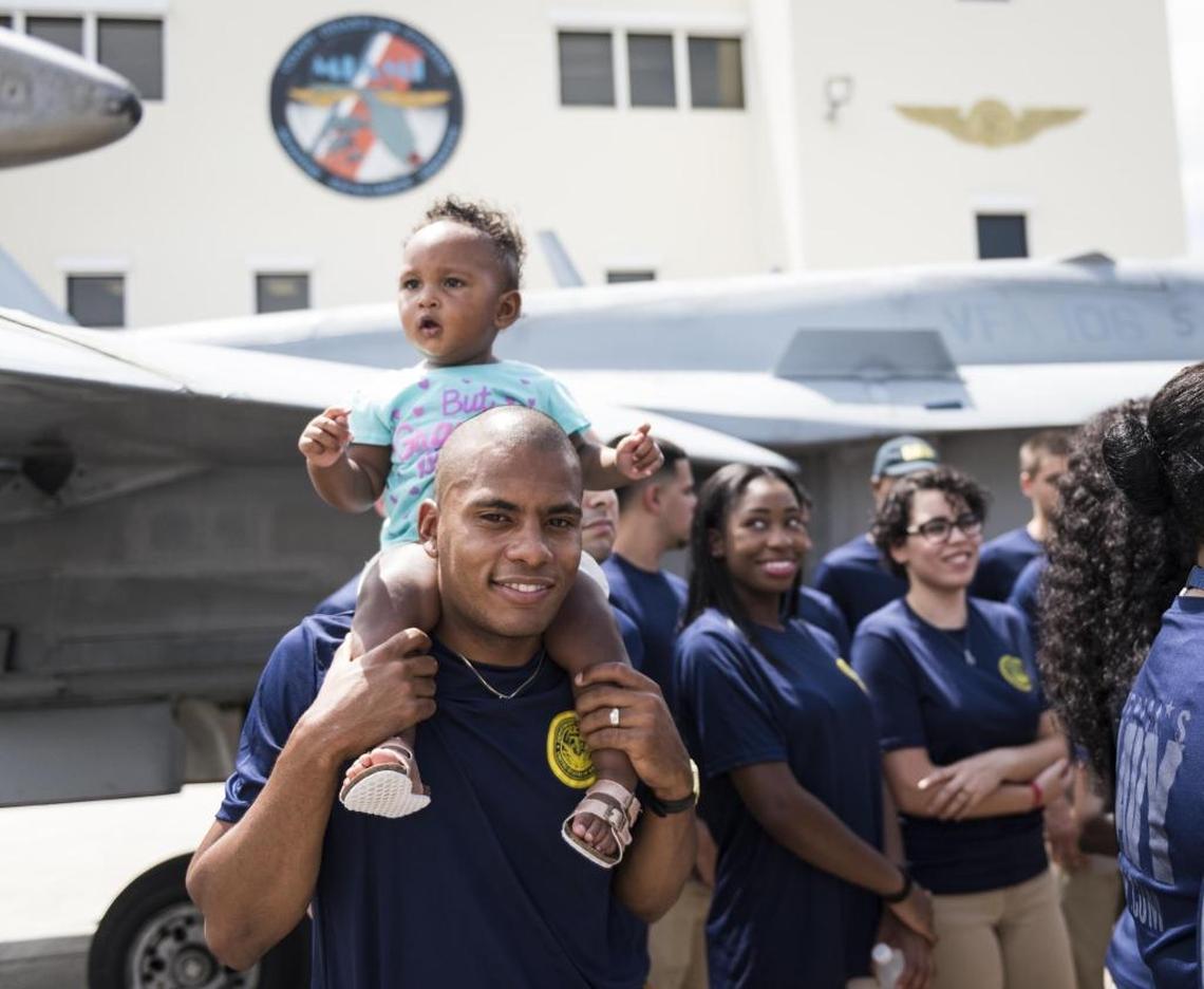 Future sailor Christopher Anria carries his daughter Chloe Anria after being sworn into the Navy at the Air and Sea Show Media Event at the Coast Guard Air Station Miami at Opa-locka Executive Airport on Friday, May 26, 2017.