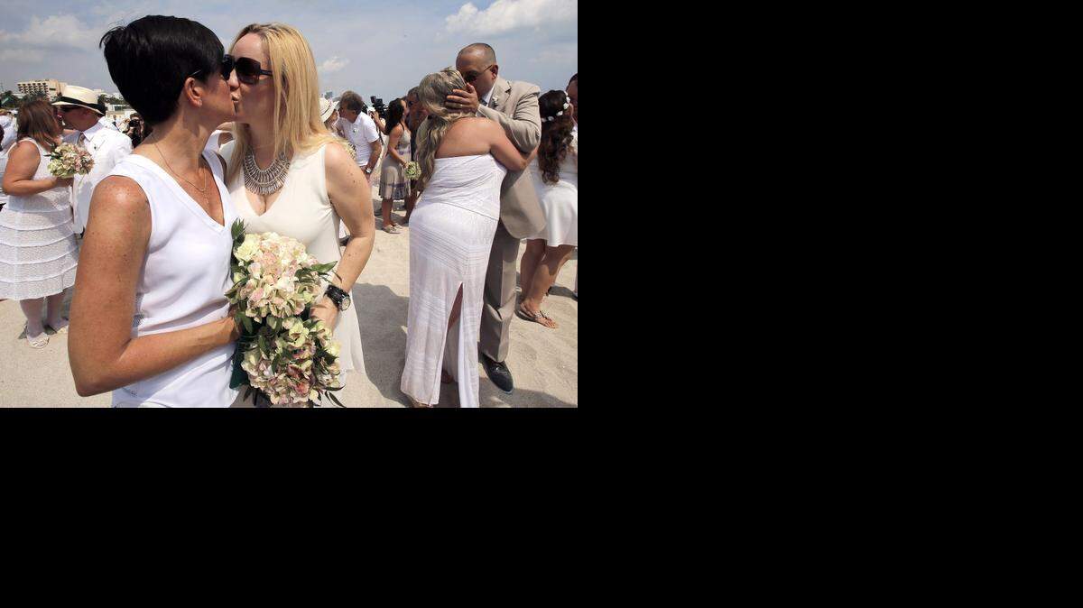 
SEALED WITH A KISS: Miami residents Cythina Casanova, left, and wife Dana Lloyd smooch along with other couples at a mass wedding and vow renewal ceremony Monday in Miami Beach.
