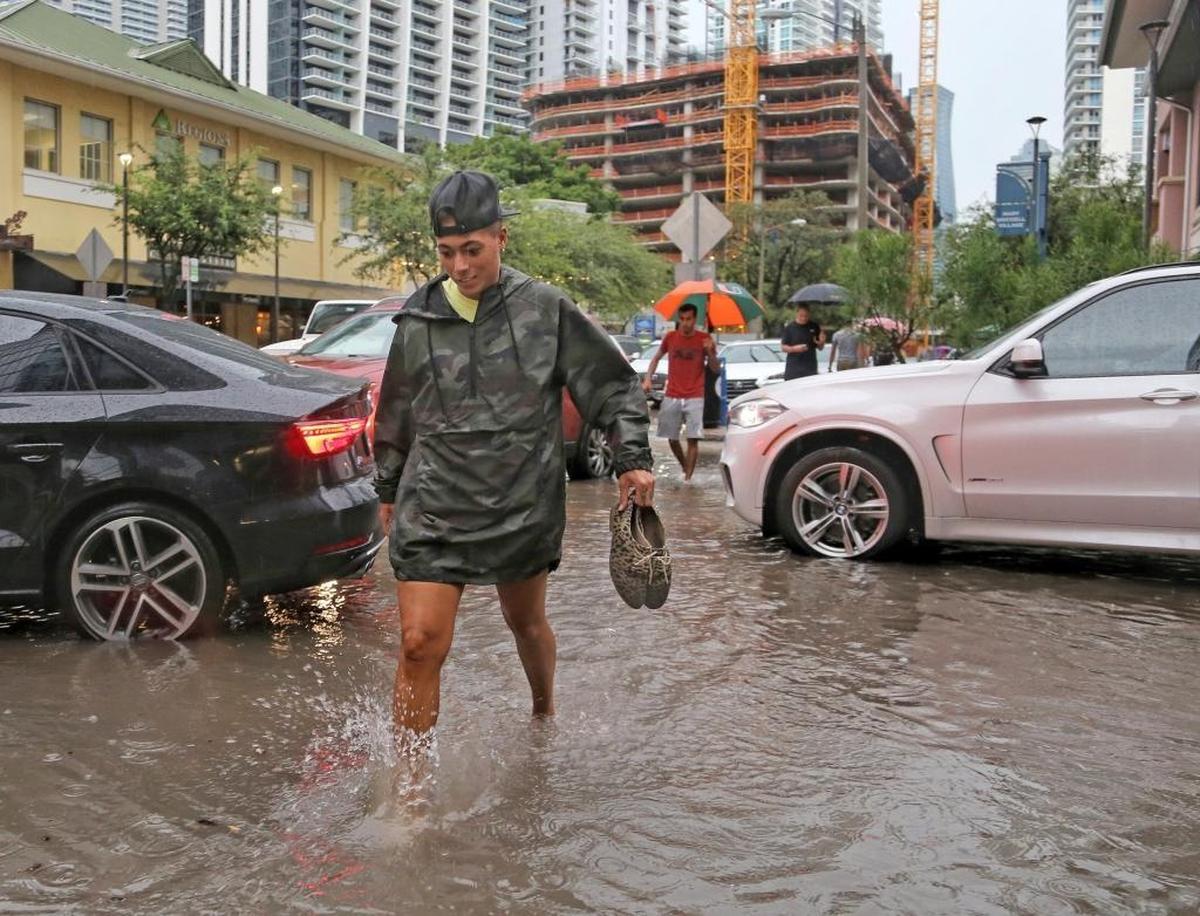 Pedestrians make their way through the flooded streets of 900 block of South Miami Avenue in Brickell as heavy rains causes havoc for motorists and commuters on Tuesday, Aug. 1, 2017, in Miami.