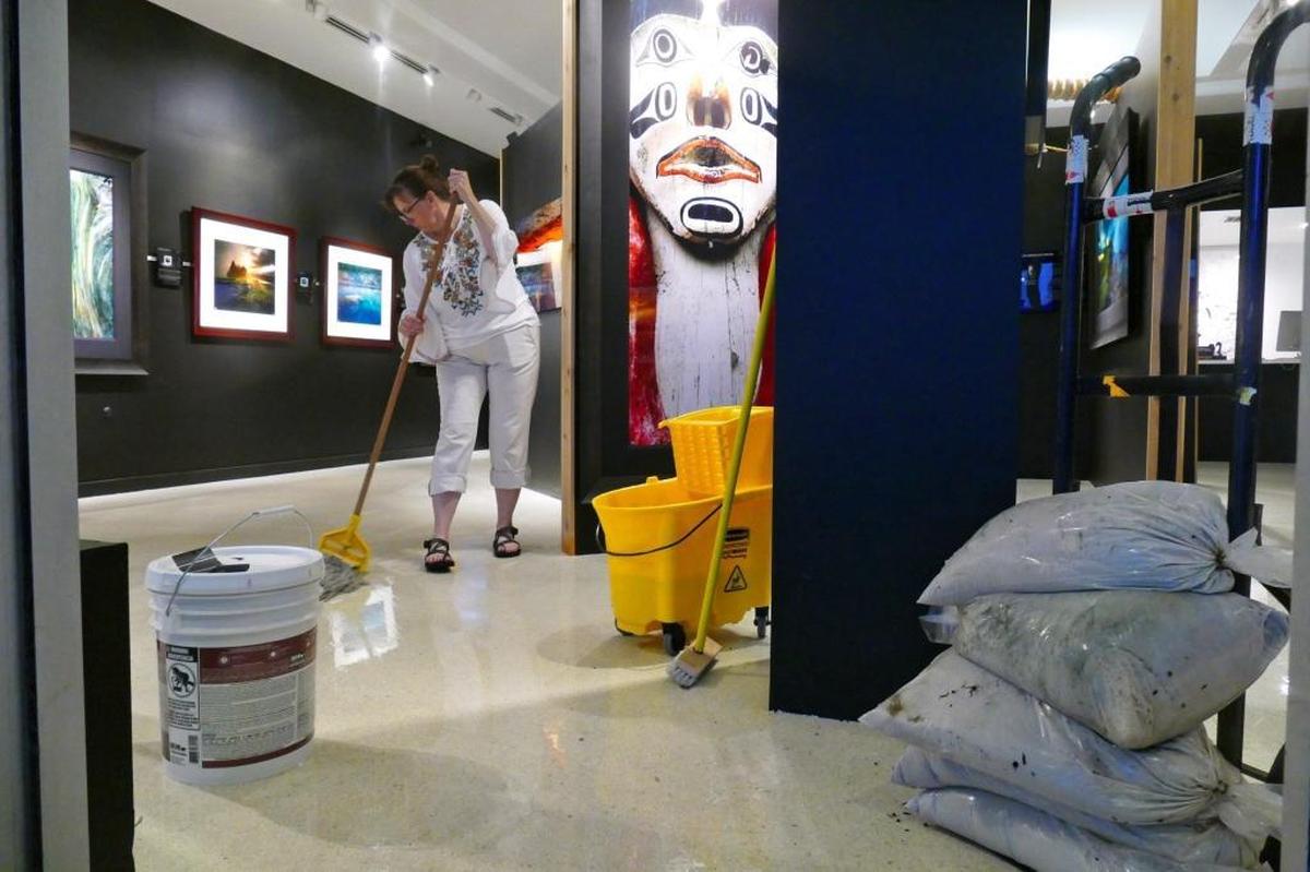 LeeAnn Lough mops rainwater out of her husband's Lincoln Road Gallery. The Rodney Lough Jr. Gallery had rainwater seep through the front and back doors during Tuesday afternoon's rainstorm. The large format photographs in the gallery were not damaged but the landlord supplied sandbags to keep more water out on Tuesday, Aug. 1, 2017.