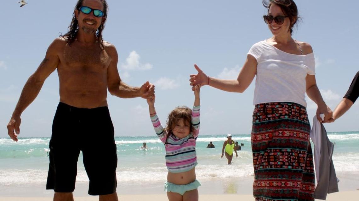 Joe Cantillo, 59, left, his granddaughter Violet Izquierdo, 3, center, and daughter Amber Cantillo, 37, right, join hands on Miami Beach's shore on Saturday morning for the Hands Across the Sand movement to say no to offshore drilling and fracking and yes to clean energy and renewables.