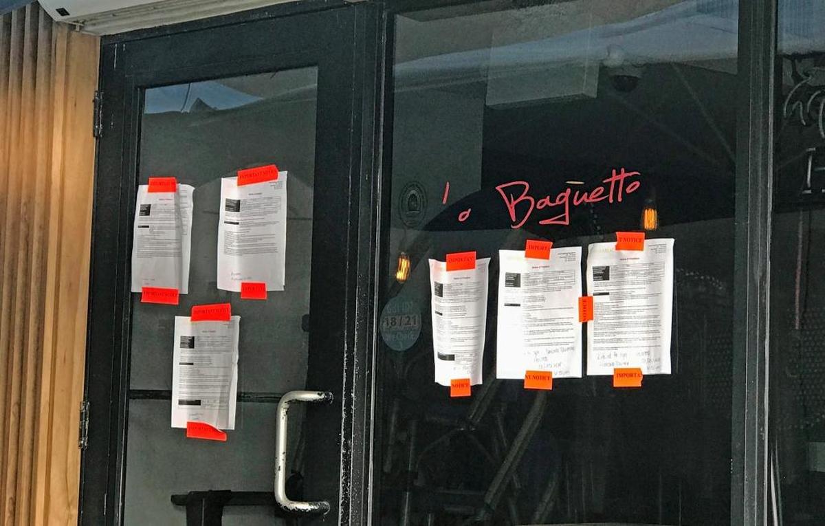 Notices on the front of La Baguette Restaurant show that it was closed by the city for failing to disclose menu prices at sidewalk cafe tables and allowing patrons to walk away with open containers of alcohol.