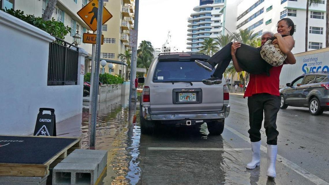 
Doorman Jose Salazar carries fellow employee Daysi Rodriguez over the tide water on Miami Beach on Friday, Oct. 9, 2015. They work at the Red South Beach Hotel.
