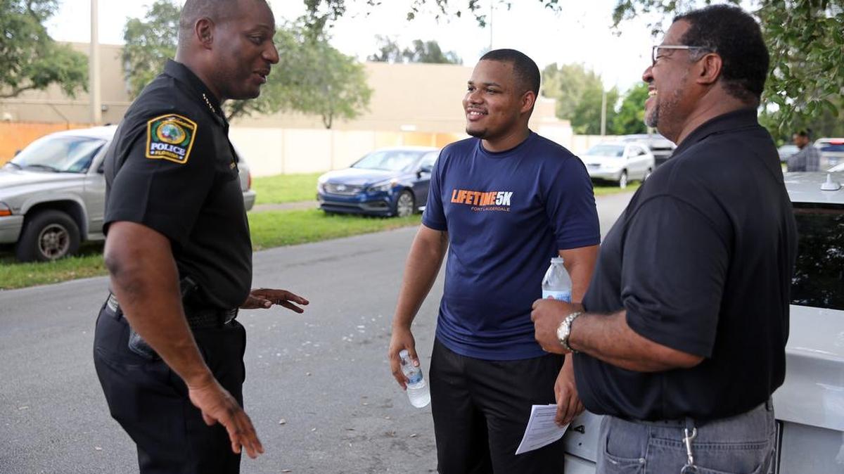 Miami Gardens Police Chief Antonio Brooklen talks with members of the community, Antquon Harris, 20, and Pastor Wendell Baskin, 57, during a ‘Coffee with a cop on the block’ event in July.