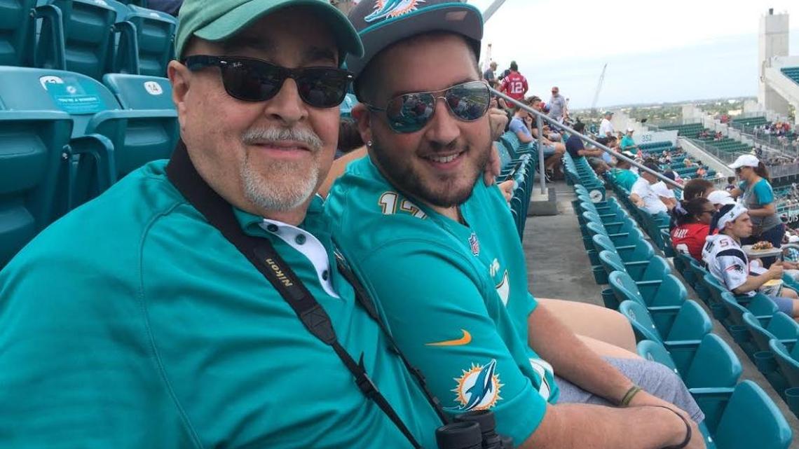 Braulio “Ozzie” Perez, left, poses with his son Chris at Sunday’s Miami Dolphins game. Perez was killed Monday when a car slammed into him as he rode his bicycle.