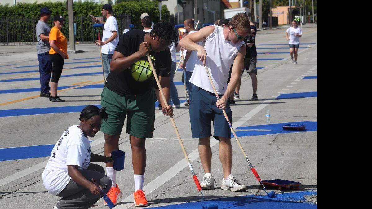 
Stacey Ferdinand, left, Keyona Hayes, center, and Derek Kocot, along with others from Miami Rise and the Opa-locka Community Development Corporation, painted streets, sidewalks and crosswalks on Ali Baba Avenue in Opa-locka on April 18. Story, 4.
