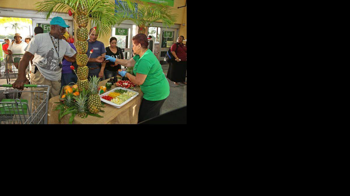 
Bernard Durham is served by Walmart employee Sonia Silvera at the ribbon-cutting ceremony for the opening of a new Walmart Neighborhood Market store in Miami Gardens on Wednesday, Jan. 7, 2015.
