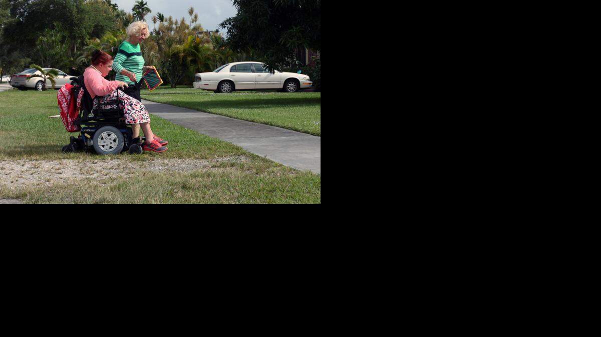 
Helen Gannon, a former Miami Springs city councilwoman, helps her daughter, Debra Ferrero, access a sidewalk in her wheel chair outside her best friend's home.
