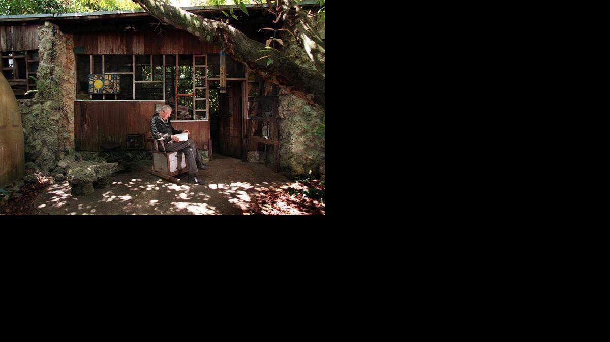 
Harry Troeger reads a book in 1999 on a rocking chair made from a couple of old beehives, at his screened-in, pine and coral rock house in South Dade.
