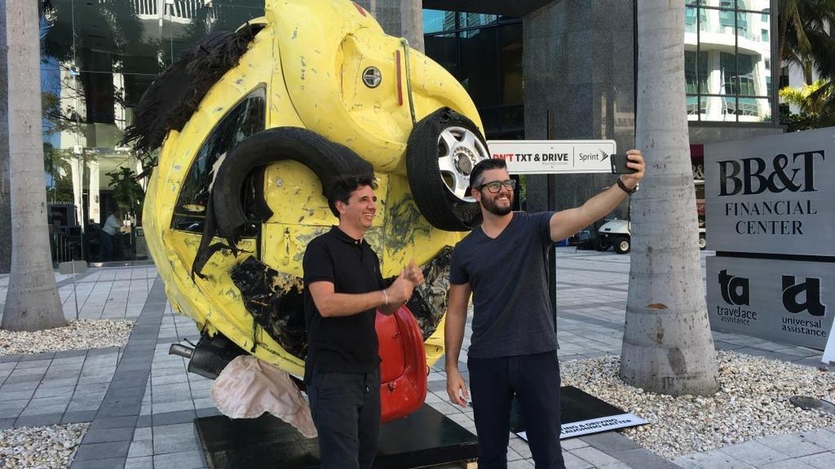 Passersby take selfies at ‘The Last Emoji’ sculpture while it was on display outside 1200 Brickell Ave. It now can be seen at 571 NW 28th St. in Wynwood.