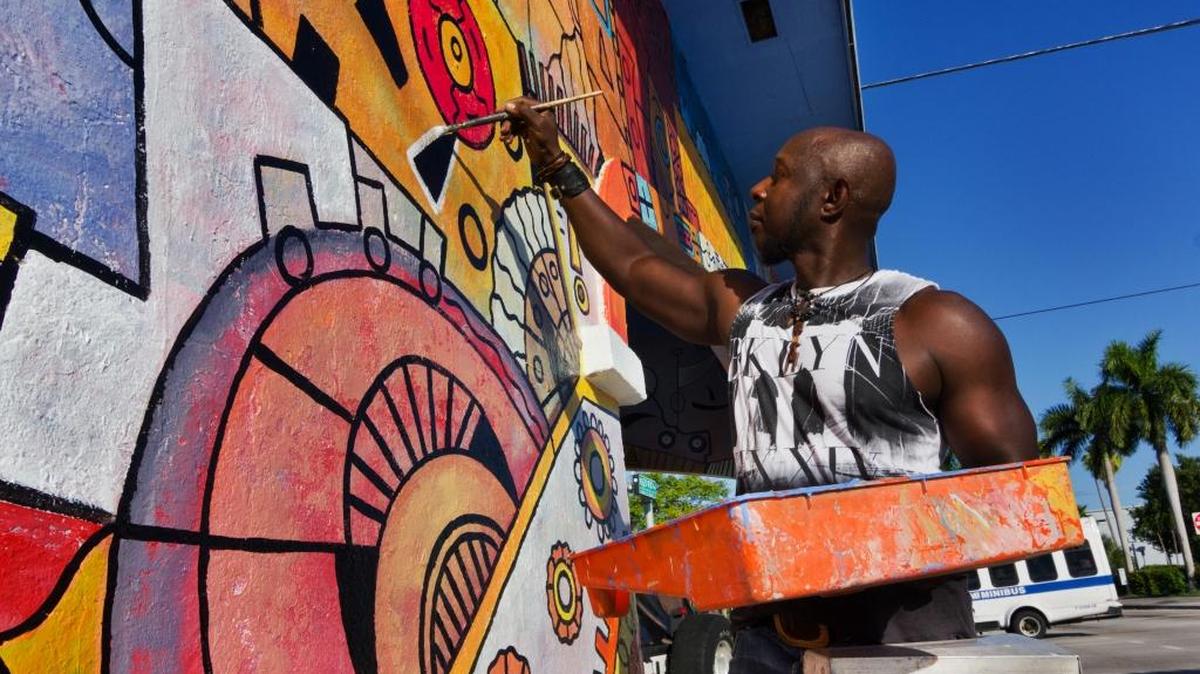 Haitian artist Turgo Bastien paints the old St. Claire Laundry and Dry Cleaners building in Little Haiti on Nov. 10.