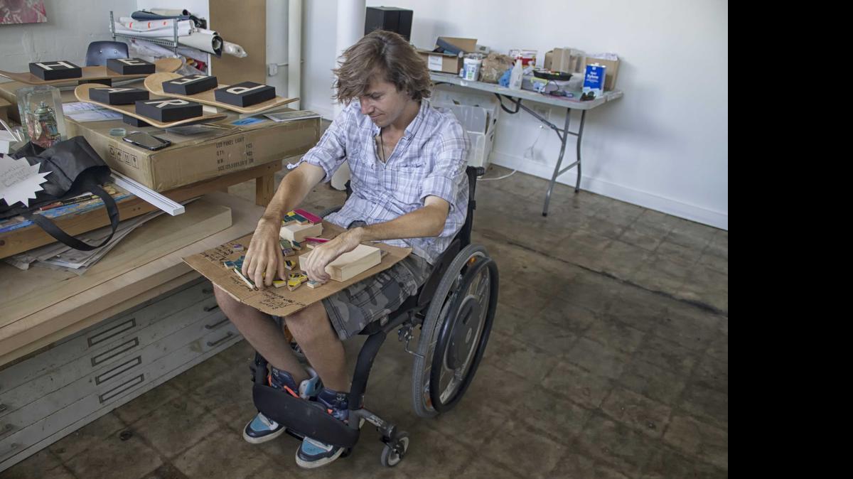 
David McCauley, who founded the nonprofit Rise Up To Cure Paralysis after he recuperated from a broken neck, works on a mosaic with repurposed skateboard parts.
