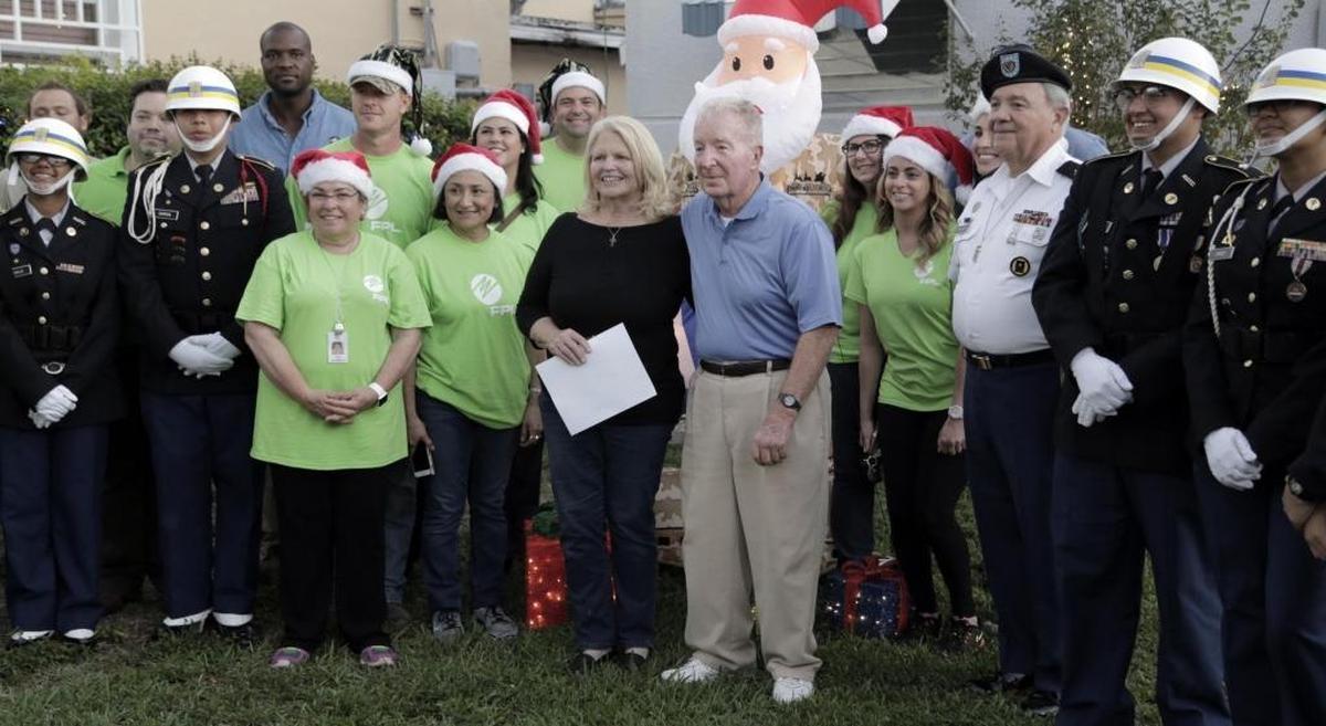 Ann and Patrick McMullan, center, pose with FPL ‘elves’ and members of the Miami Senior High ROTC in front of their newly decorated house on Dec. 5, 2017. FPL surprised Patrick, a former U.S. Marine, by outfitting the home with energy-efficient holiday decorations.