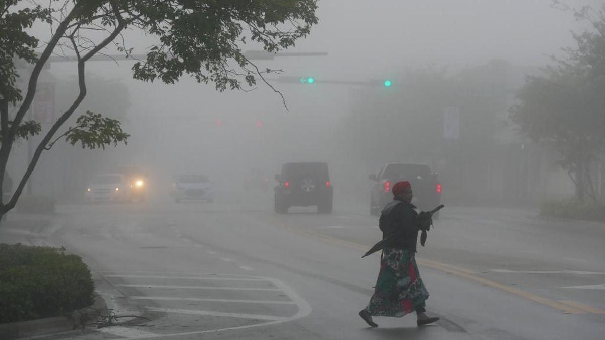 A woman crosses NE 2nd Ave. just north of NE 96th Street, in Miami Shores, in dense fog Sat. Jan. 16, 2016.
