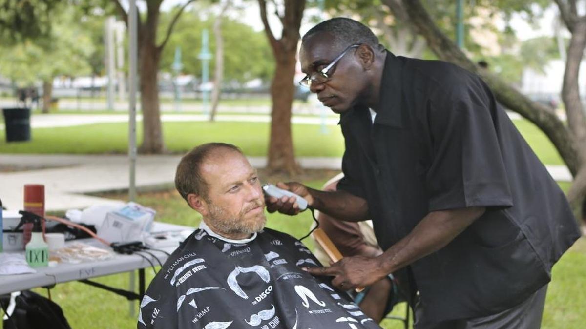 
Lynnward McClyde, right, a formerly homeless Miami resident, shaves off Jerry Smith's beard after giving him a haircut on Friday, Oct. 16, 2015, at the City of Miami Homeless Citizen's Stand Down at Lummus Park. McClyde was among hundreds of volunteers who helped homeless people get off the streets at the event, at 404 NW Third St. Volunteers handed out food, clothing, offered health exams and other social services. 
