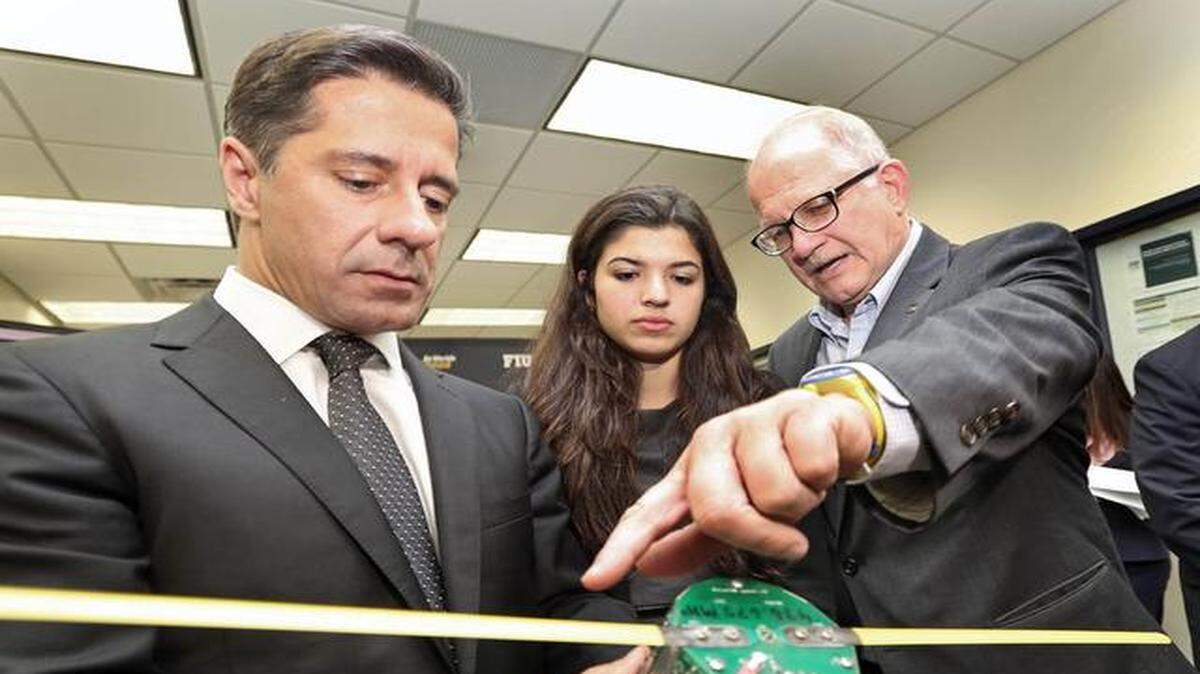 
Miami-Dade County Public Schools Superintendent Alberto Carvalho-(L) holds up a flight ready satellite built by students from David Lawrence Jr K-8, Alonso and Tracy Mourning High School and FIU as Mourning High senior Briana Hawryluk and University President Mark Rosenberg view the actual satellite before the Satellite Demo press conference on Friday November 21, 2014
