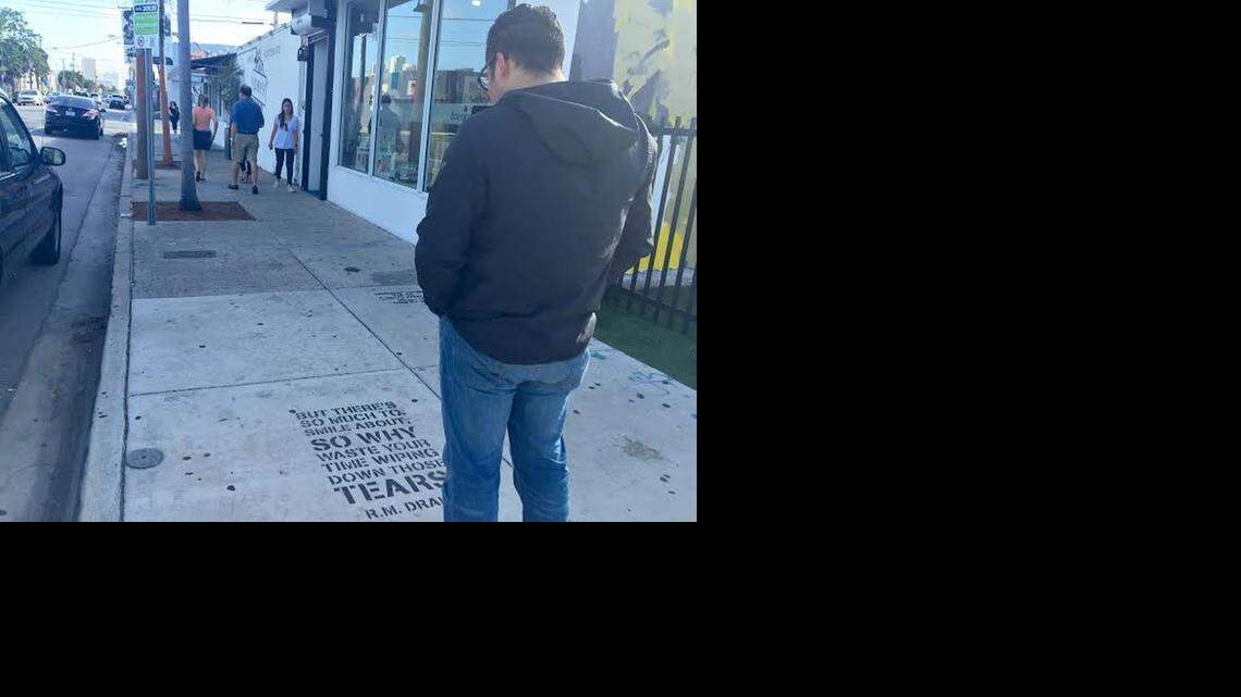 
Poet Robert Macias stands outside of Wynwood Walls in Wynwood, where he has spray painted one of his poems on the sidewalk.
