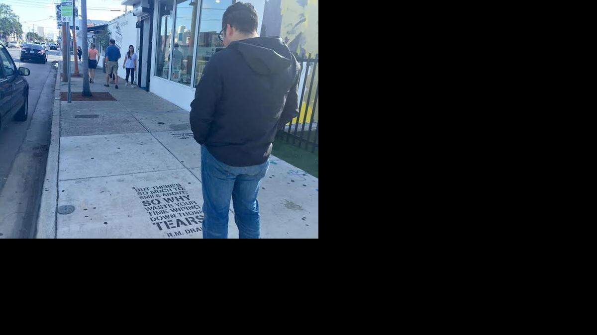 
Poet Robert Macias stands outside of Wynwood Walls in Wynwood, where he has spray painted one of his poems on the sidewalk.
