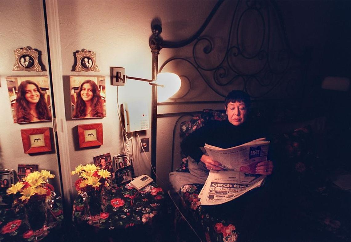 Sue Billig reads the paper in her bedroom near a photo of her daughter Amy and the telephone.