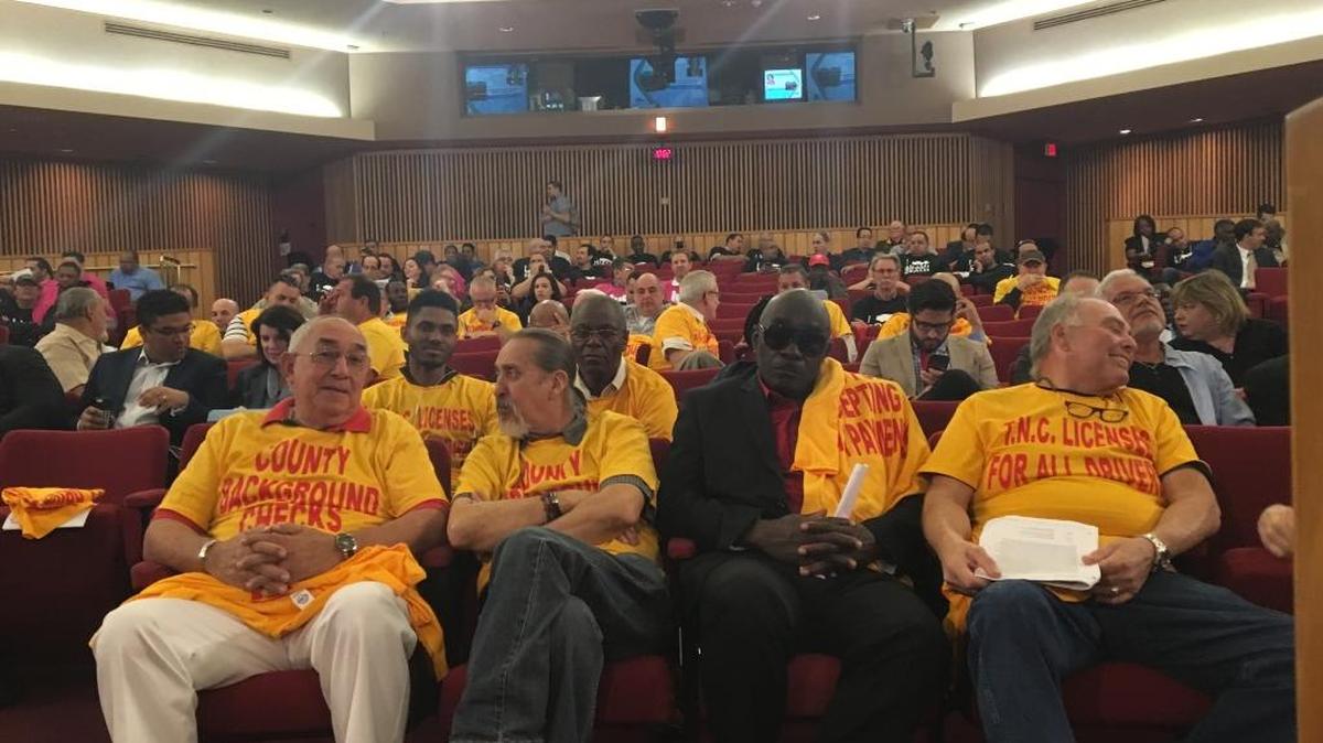 Taxi advocates in yellow T-shirts took the first row in a crowded session Thursday on Miami-Dade legislation designed to legalize Uber and other app-based ride services that already compete with cabs in South Florida. Photographed are, from left to right, Coral Cab manager William Pratt, drivers Humberto Becerra and Rafael Gerard, and owner Jerry Moskowitz.