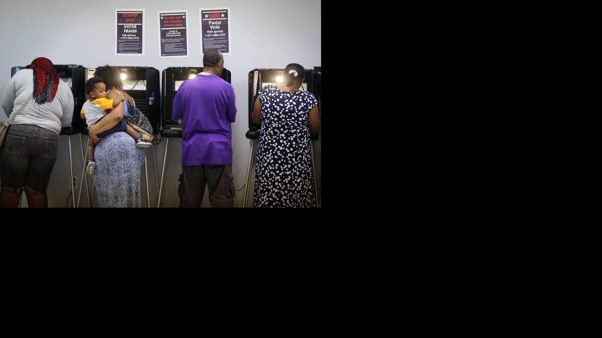 
One-year-old Robert Carter, patiently clings to his mother, Carnola Garrett as she voted at North Miami's Sunkist Grove Community Center in a special election last November. The City Council is proposing a change in the city’s general election date to coincide with the countywide election.
