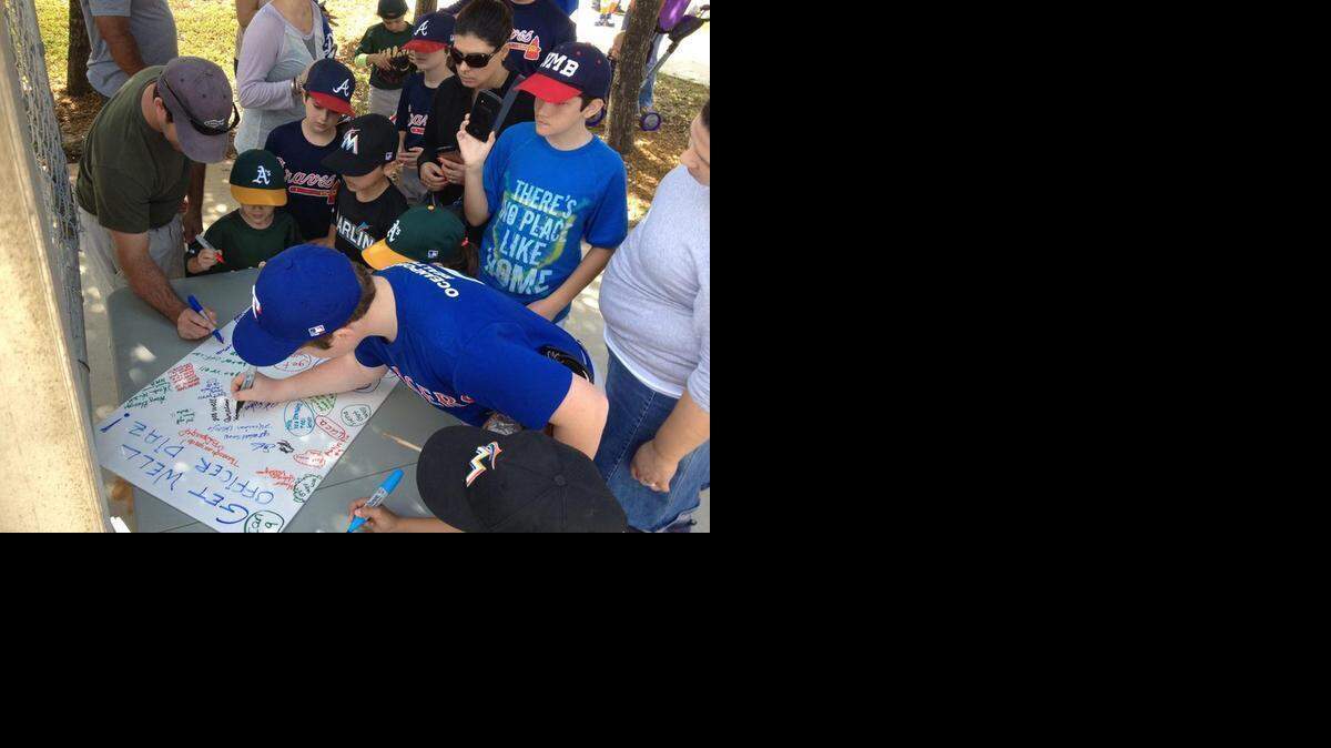 
North Miami Beach little league players sign get-well wishes for wounded North Miami Beach police officer Lino Diaz. The card was delivered to the hospital.
