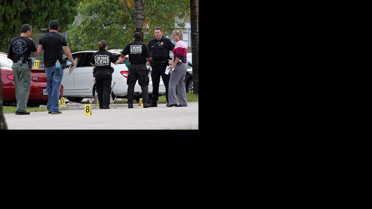 
Crime scene technicians and police investigate the scene of a North Miami Beach drive-by shooting that left one man dead and another wounded.
