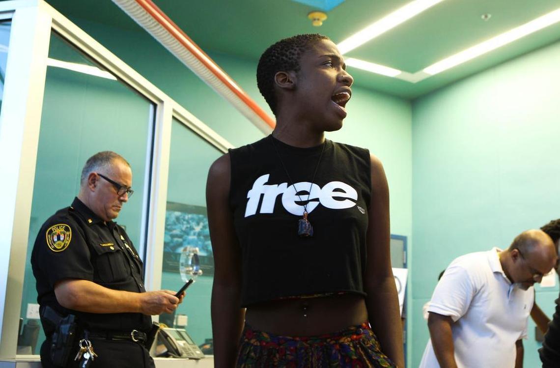 Jodi Henningham, center, was one of several protestors at the North Miami Police Department after the shooting of Charles Kinsey. Cmdr. Emile Hollant, left, was told he was being fired by the city after an internal affairs investigation.