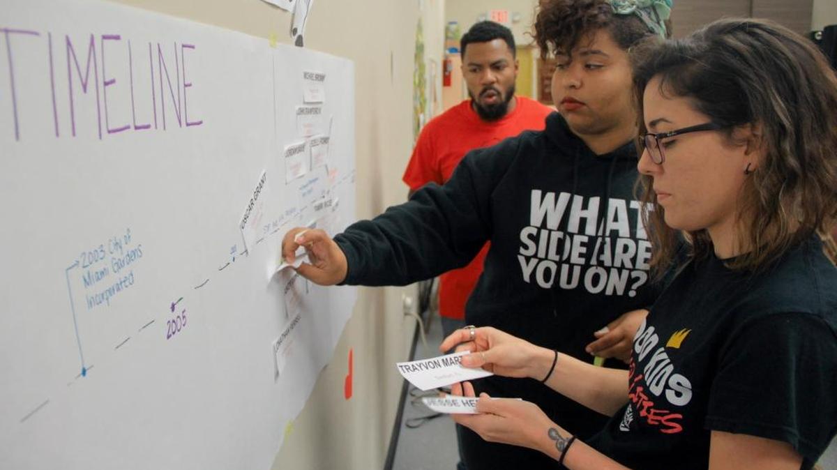 
File art: Dream Defenders then-executive director, Phillip Agnew, and Dream Defenders members Shamile Louis, center, and Arely Lozano-Baugh, right, post notes written by members of the Miami Gardens community onto a poster on Feb. 21, 2015.