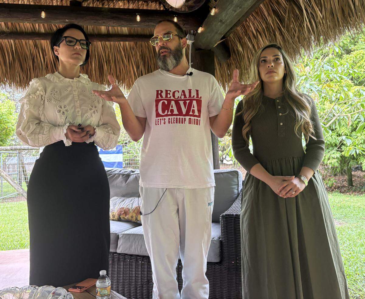 Alex Otaola, center, announces his effort to recall Miami-Dade Mayor Daniella Levine Cava has failed by not meeting the required number of voter signatures to trigger a recall election. He made the announcement at a press conference outside his home near Homestead on Thursday, May 13, 2026. He is flanked by two of his lawyers, Lisbet Velazquez, left, and Leslie Perez Perez.