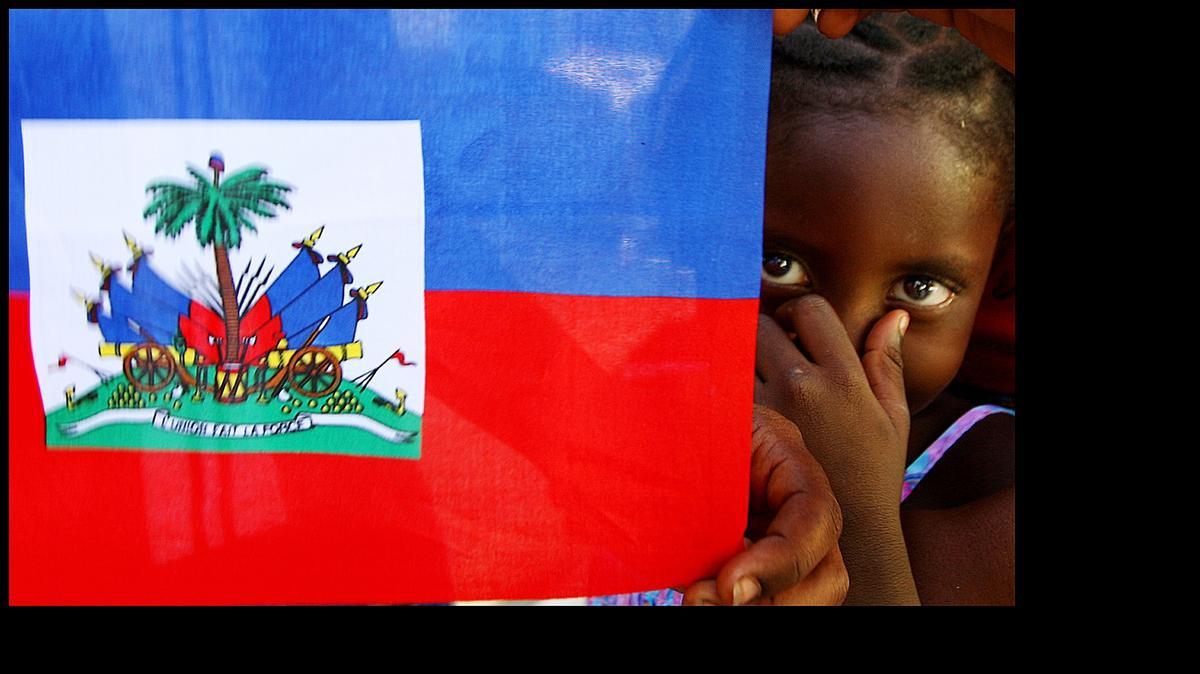 
Malik Desange of Arcahaie, Haiti peers from behind a Hatian flag on May 18, 2010. Arcahaie is the birthplace of the Haitian flag.
