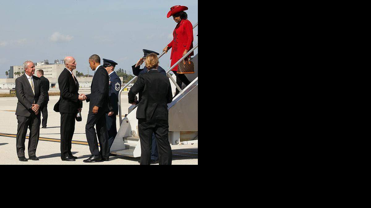 
President Barack Obama is welcomed by Miami-Dade Mayor Carlos Gimenez and Florida Gov. Rick Scott as he arrives at Miami International Airport with Congresswoman Frederica Wilson for a town hall meeting on immigration at Florida International University on Wednesday, Feb. 25, 2015.
