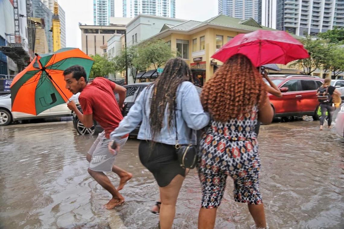 Pedestrians make their way through the flooded streets of 900 block of South Miami Avenue in Brickell as heavy rains causes havoc for motorists and commuters on Tuesday.