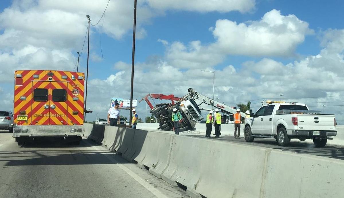 A truck lies tipped over along State Road 836, by Northwest 37th Avenue, on Wed., Oct. 11, 2017. A dispatcher with the Miami Fire Department said a man on the truck was injured from a fall during the incident.