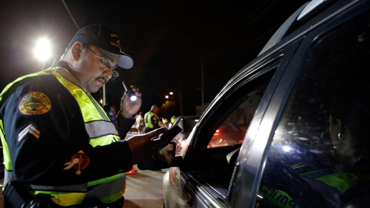 
Miami police officer Luis Ortiz looks at a driver’s license he requested from a motorist, Jan. 29, 2015. Drivers who recently changed their address online and requested an updated license from the state may be receiving a new license but with their old address because of a computer problem. 
