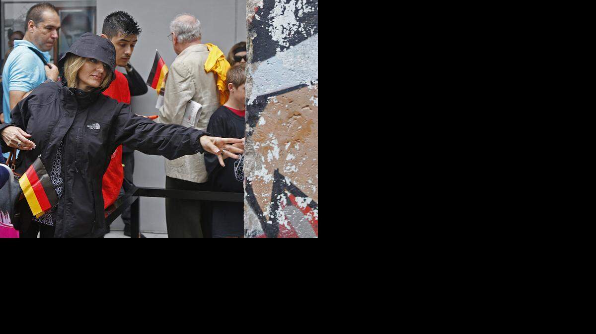 
Andrea Silbermann Paskow, whose father was German, reaches out to touch the piece of the Berlin Wall. Miami Dade College unveiled a section of the Berlin Wall as a gift from the Federal Republic of Germany, on Sunday, November 9, 2014.

