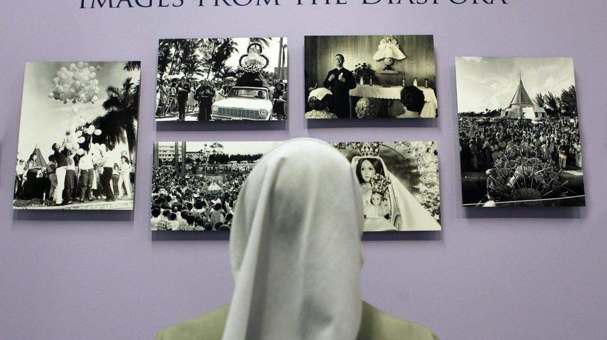 
Sister Ondina Cortés looks at some photographs that make up part of a photo exhibit on the history of Our Lady of Charity, Cuba’s patron saint, on display at the library at St. Thomas University.
