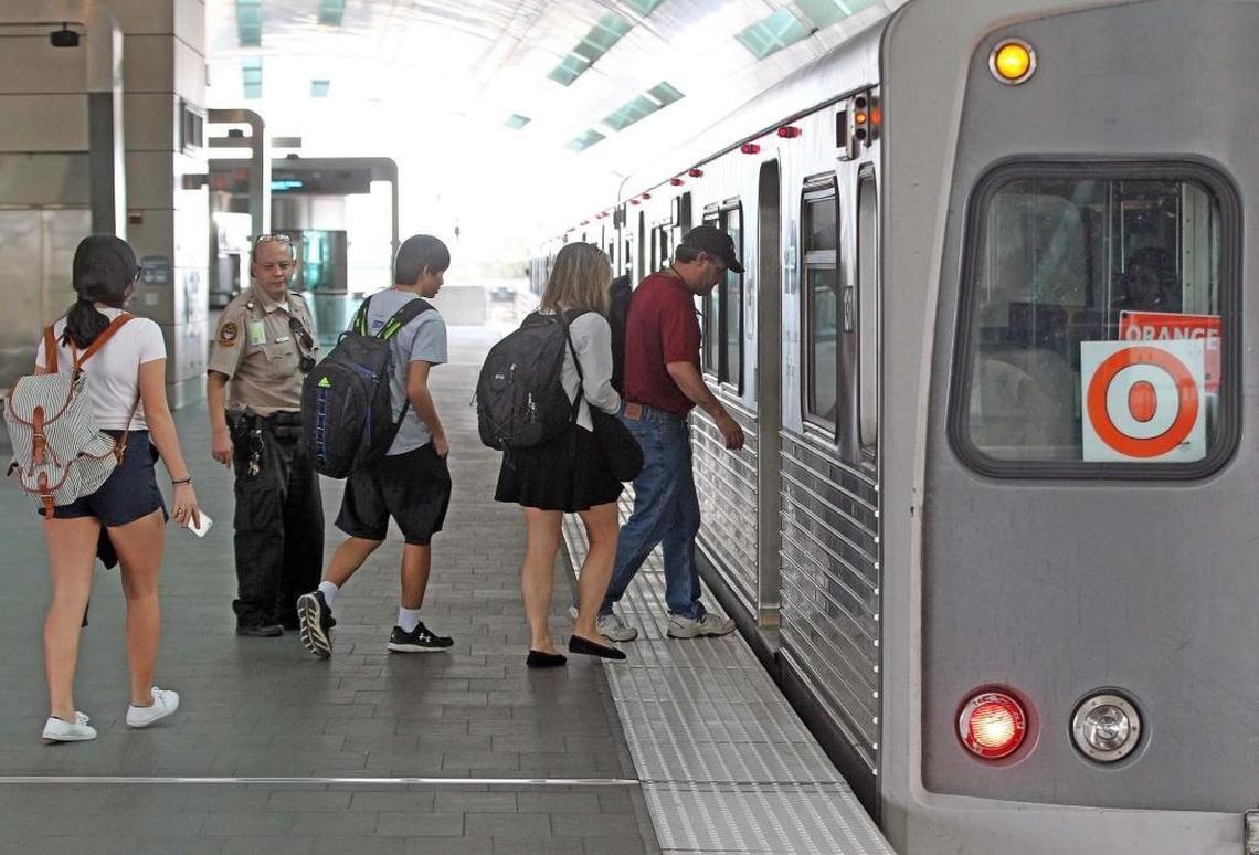 Airport passengers and commuters board the Metrorail Orange Line at Miami International Airport. The line is ending its brief experiment with more frequent trains.
